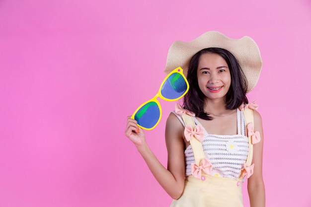 Una hermosa mujer asiática con un sombrero y grandes gafas con una rosa.