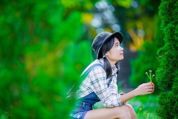 Una hermosa mujer asiática con un sombrero para relajarse y disfrutar en el jardín verde como telón de fondo.