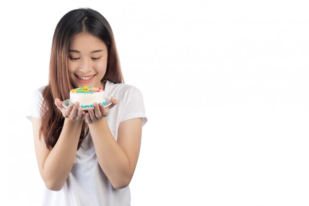 Hermosa mujer asiática con una sonrisa feliz sosteniendo un pastel en la mano