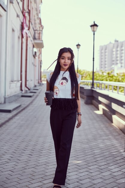 Hermosa mujer asiática en vestido de moda caminando por la calle brillante