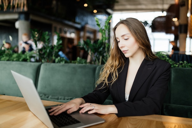 Hermosa mujer atractiva en el café con un portátil tomando un café