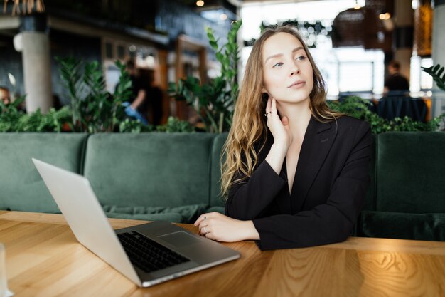 Hermosa mujer atractiva en el café con un portátil tomando un café