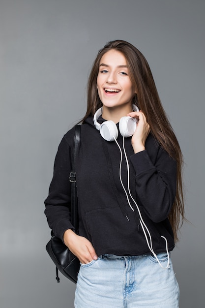 Hermosa mujer bailando en auriculares mientras escucha la música sobre la pared blanca