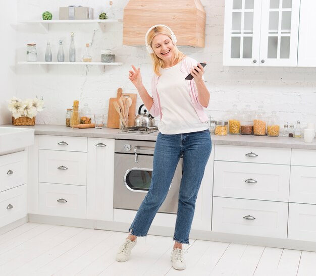 Hermosa mujer bailando con música en la cocina