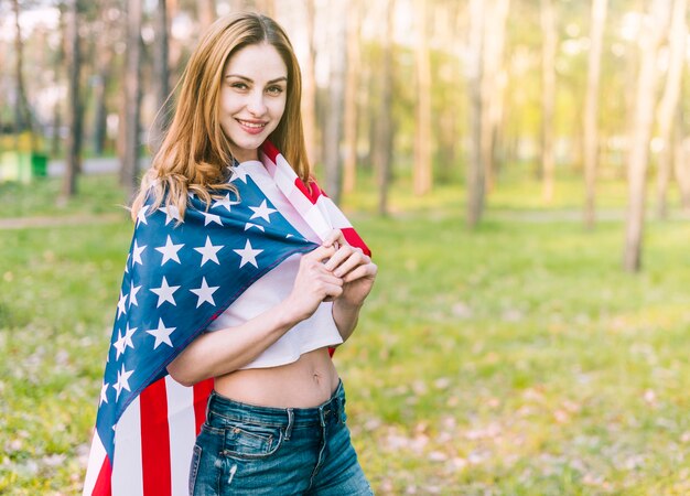 Hermosa mujer con bandera americana en los hombros.