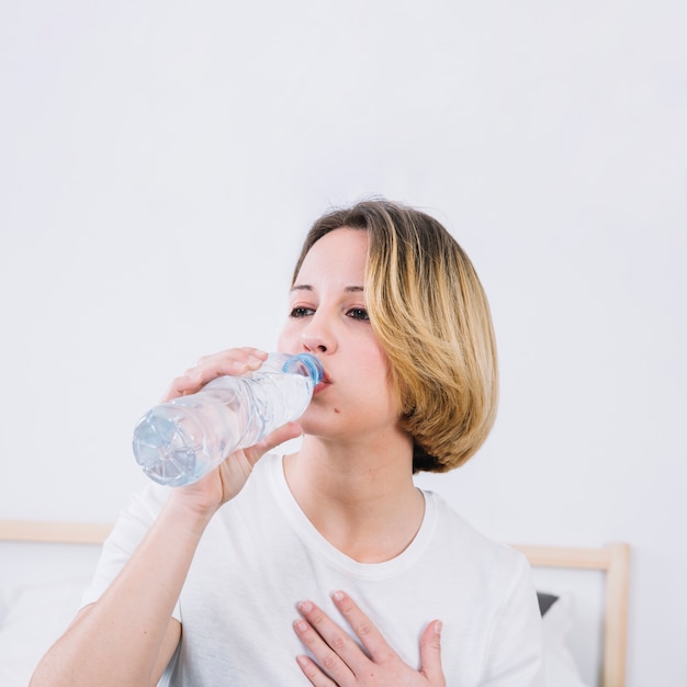 Hermosa mujer bebiendo agua de botella