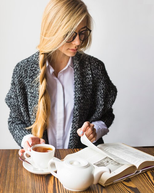 Hermosa mujer bebiendo té y leyendo