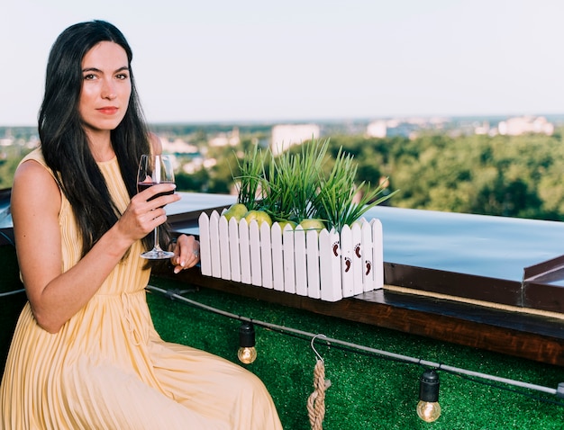 Hermosa mujer bebiendo vino en la azotea