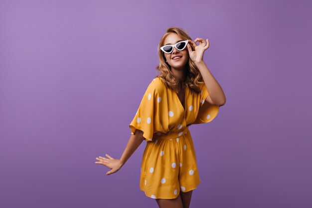 Hermosa mujer bien vestida sonriendo en púrpura. Retrato de dama encantadora en traje amarillo.