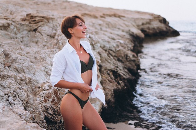 Hermosa mujer en bikini posando junto al océano