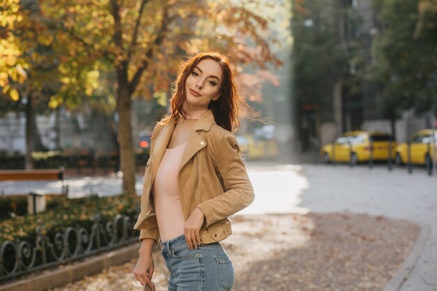 Hermosa mujer blanca en chaqueta beige pasar tiempo libre en el parque