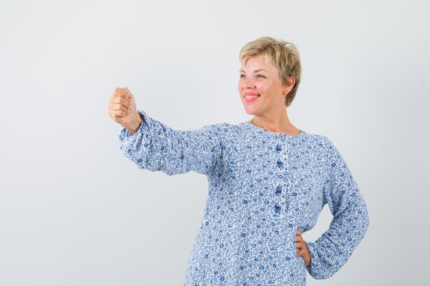 Hermosa mujer en blusa estampada posando como sosteniendo un espejo y luciendo bonita, vista frontal.