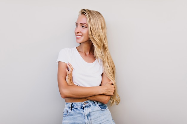 Hermosa mujer bronceada con peinado largo mirando a otro lado. Sensual mujer alegre sonriendo