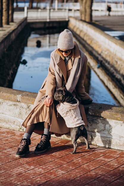 Hermosa mujer con bulldog francés caminando en el parque