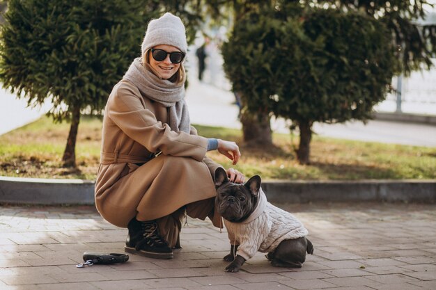 Hermosa mujer con bulldog francés caminando en el parque