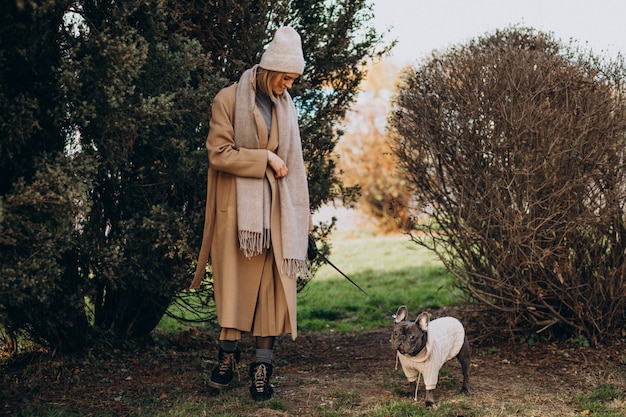 Hermosa mujer con bulldog francés caminando en el parque