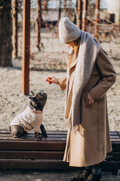 Hermosa mujer con bulldog francés caminando en el parque