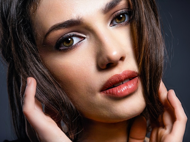 Hermosa mujer con cabello castaño. Modelo atractivo de ojos marrones. Modelo de moda con un maquillaje ahumado. Closeup retrato de una mujer bonita mira a cámara.