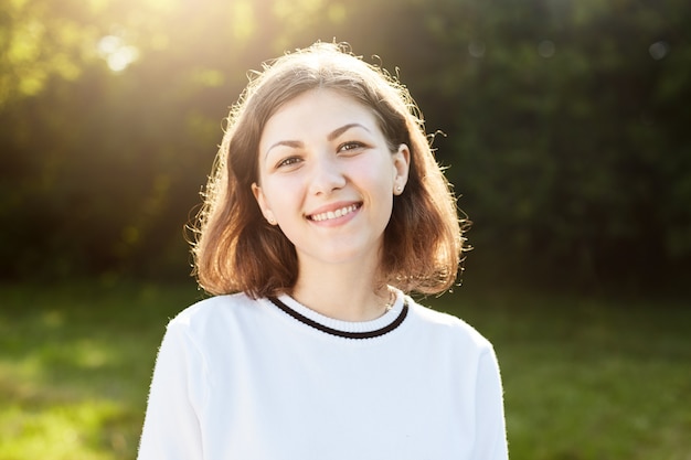 Hermosa mujer con cabello corto y apariencia atractiva sonriendo gratamente a la cámara