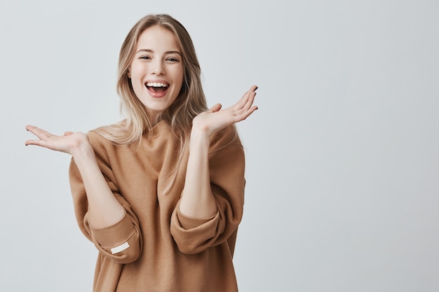 Hermosa mujer con cabello largo rubio con expresión facial emocionada y feliz