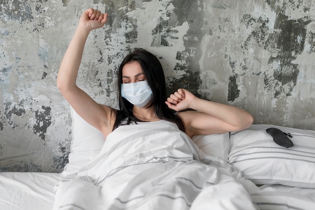 Hermosa mujer en la cama con mascarilla