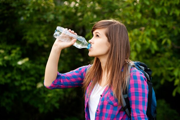 Hermosa mujer caminante agua potable en el bosque