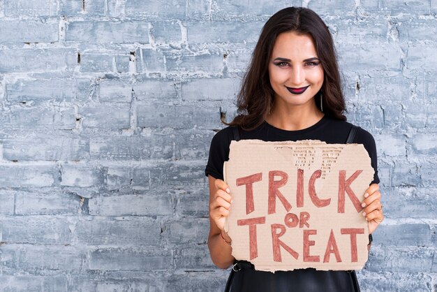 Hermosa mujer con cartel de truco o trato