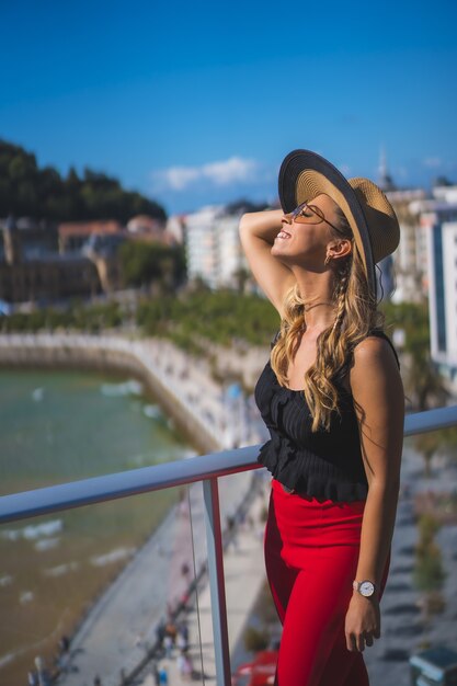 Hermosa mujer caucásica blanca felizmente de pie en el balcón de la habitación del hotel con vistas al mar