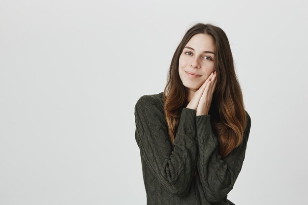 Hermosa mujer caucásica con tierna sonrisa, apoyada en las palmas, toque la piel suave y limpia