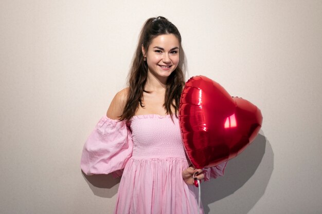 Hermosa mujer celebrando el día de San Valentín con un vestido rosa con globos
