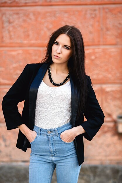 Hermosa mujer en una chaqueta junto a la pared