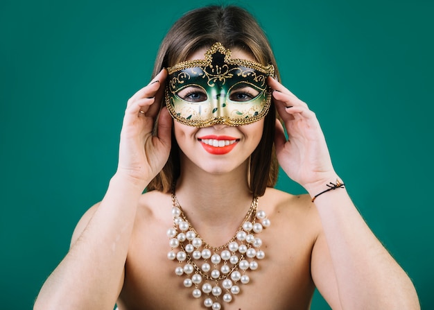 Hermosa mujer con collar de cuentas y máscara de carnaval sobre fondo verde