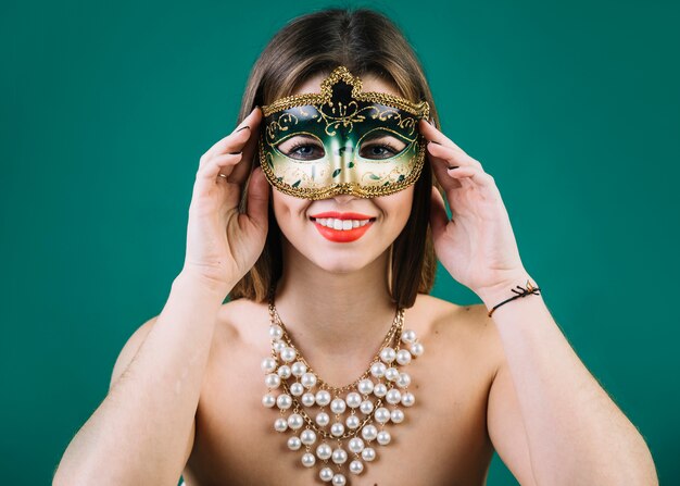 Hermosa mujer con collar de cuentas y máscara de carnaval sobre fondo verde