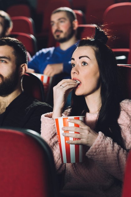 Foto gratuita hermosa mujer comiendo palomitas de maíz en el cine