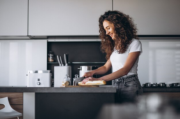 Hermosa mujer comiendo pan fresco en la cocina