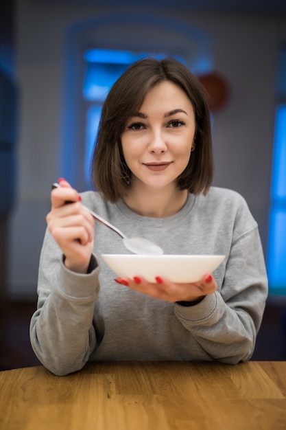 Foto gratuita hermosa mujer comiendo su desayuno porrige con frutas en su cocina