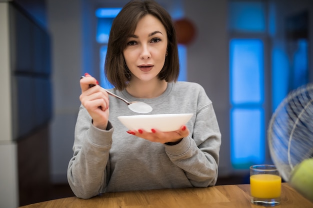 Foto gratuita hermosa mujer comiendo sus cereales para el desayuno en su cocina