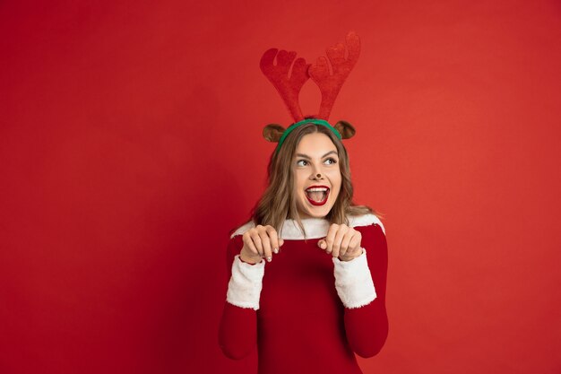 Hermosa mujer como ciervos de Navidad aislado en concepto de superficie roja de vacaciones de humor de invierno de año nuevo