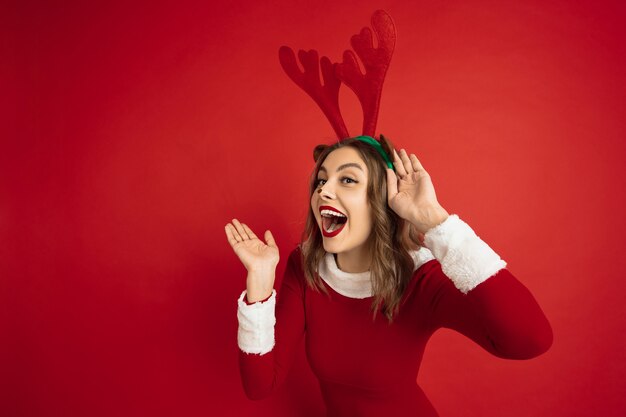 Hermosa mujer como ciervos de Navidad aislado en pared roja