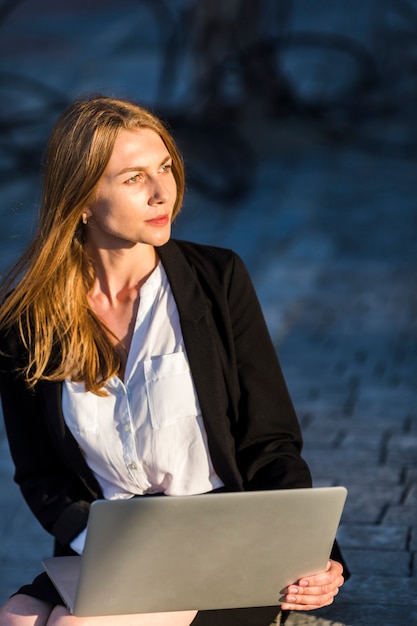 Foto gratuita hermosa mujer con una computadora portátil al aire libre