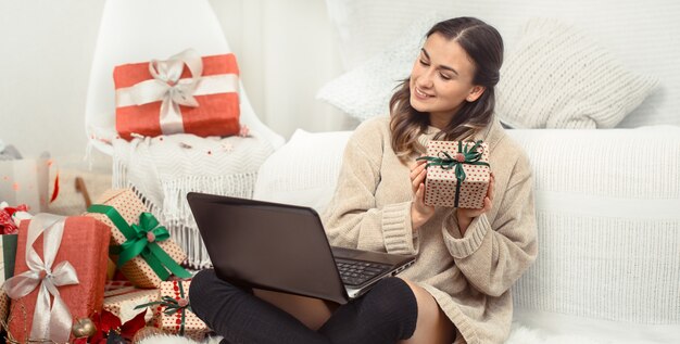 Hermosa mujer con computadora y regalos de Navidad.