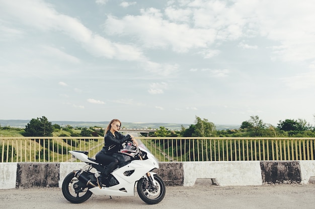 Hermosa mujer conduciendo una moto en una carretera