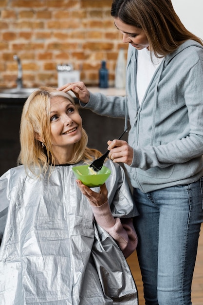 Hermosa mujer consiguiendo su cabello teñido por peluquero en casa