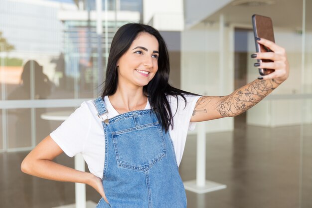 Hermosa mujer contenta tomando selfie con smartphone