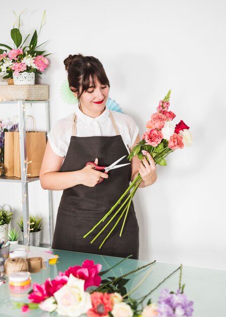 Hermosa mujer cortando ramitas de flores con tijeras.