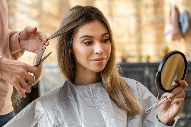 Hermosa mujer cortándose el pelo en casa por peluquero