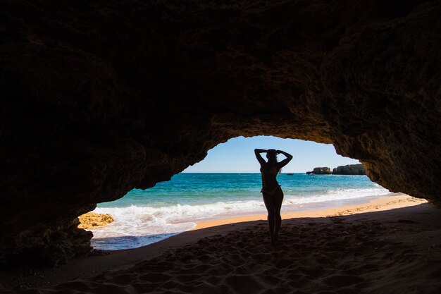 Hermosa mujer con cuerpo sexy posando cerca de rocas en la playa