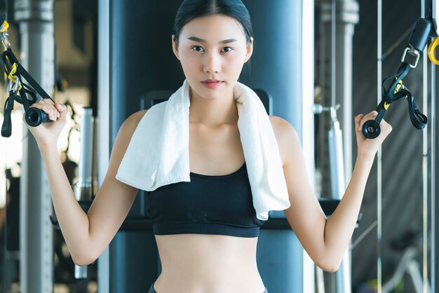Hermosa mujer deportiva asiática entrena con máquina de pesas para hacer ejercicio en fitness hermosa mujer levanta mancuernas pesadas mientras entrena en el fitness Concepto deportivo bodu builder estilo de vida saludable