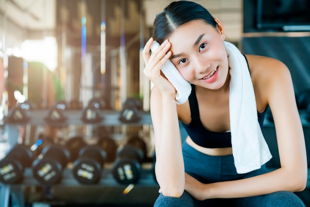 Hermosa mujer deportiva asiática sentada relajándose después del entrenamiento probado con el concepto de ideas saludables de entrenamiento con pesas