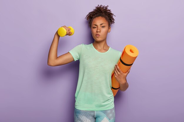 Hermosa mujer deportiva entrena bíceps, levanta mancuernas